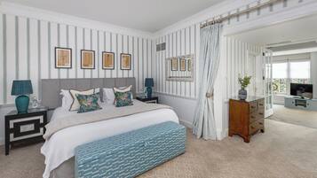 A bedroom with a bed, bedside tables, a dresser, a bench, and a view of the outside.