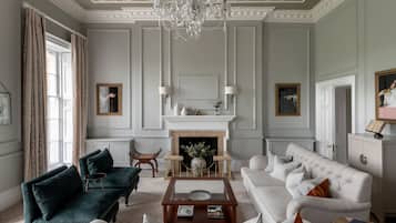 Una sala de estar amplia con chimenea, muebles elegantes y un candelabro.