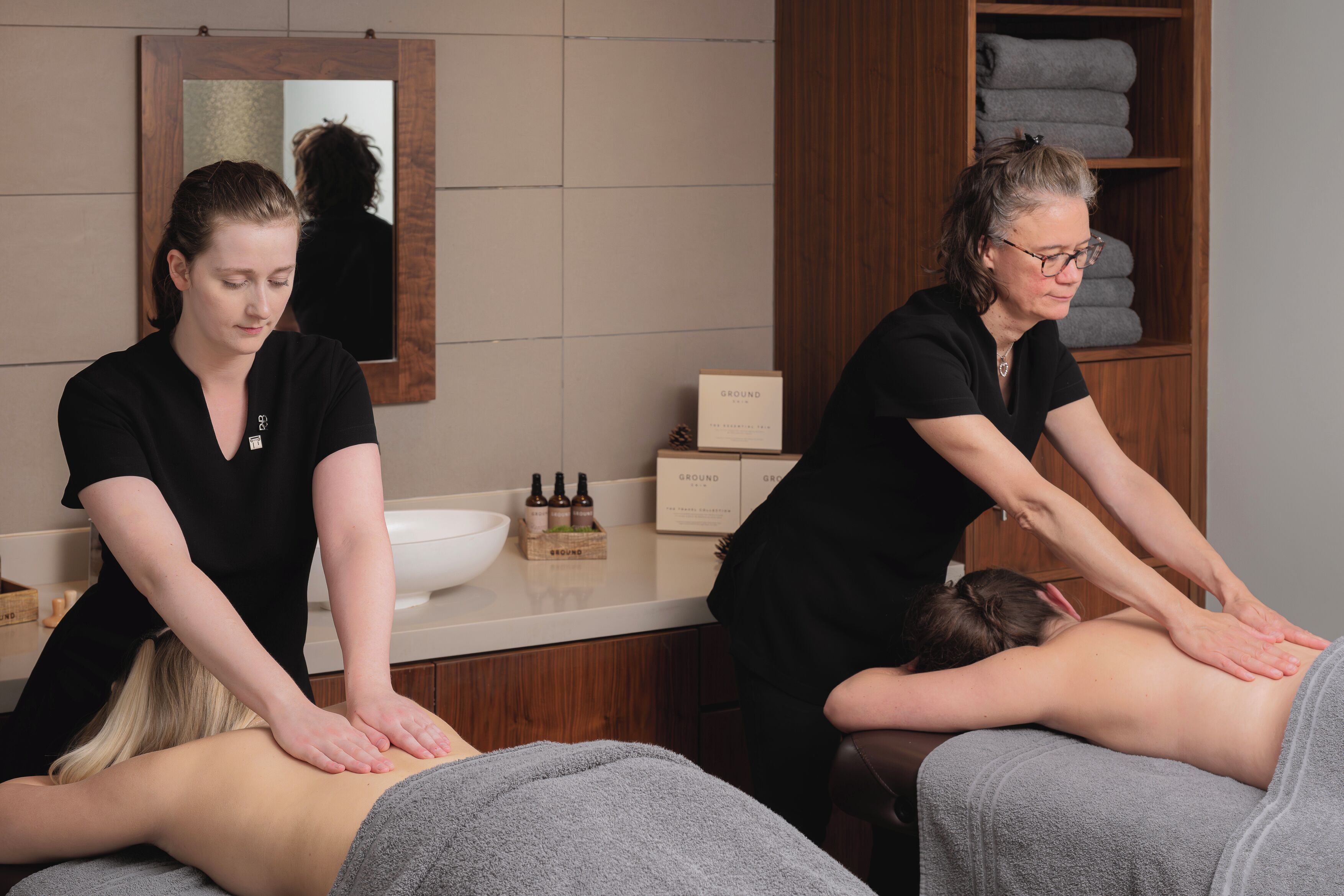 A spa setting with two masseuses attending to clients.