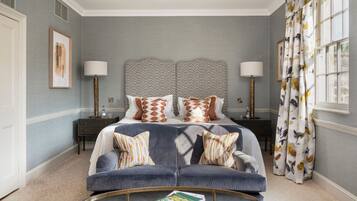 A bedroom with a bed, two bedside tables, a sofa, a coffee table, and a window with curtains.