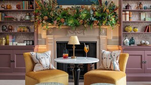 A cozy living room with two armchairs, a fireplace, and a bookshelf filled with books and decorative items. - The Royal Crescent Hotel & Spa (Bath)