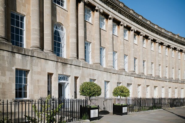 A historic building with a symmetrical facade, large windows, and a black iron fence.