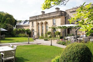 A courtyard with a building featuring arched windows and a covered outdoor seating area.