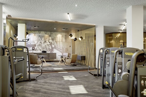 Un gimnasio con equipo de ejercicio, una zona de recepción y una pared con un mural.