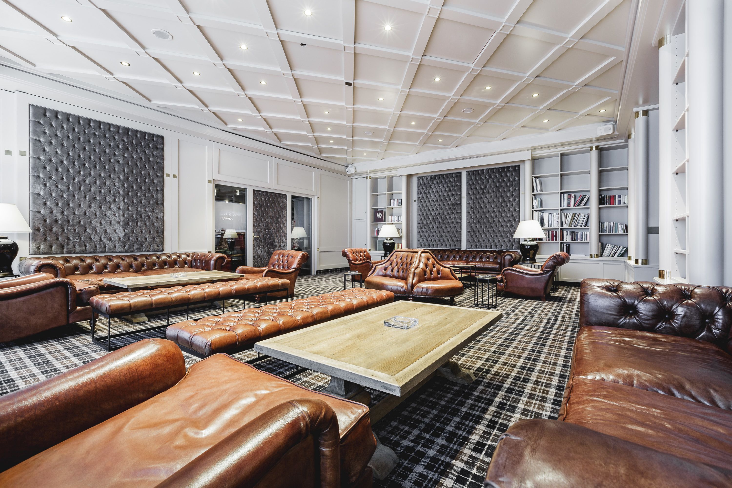 A spacious lounge area with leather sofas and armchairs, a central coffee table, and a patterned carpet.