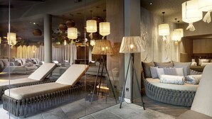 Un área de lounge moderna con asientos acolchados, separador de vidrio e iluminación ambiental.