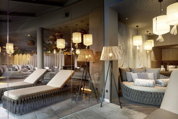 Un espace de détente moderne avec des sièges confortables, une cloison en verre et un éclairage d’ambiance.