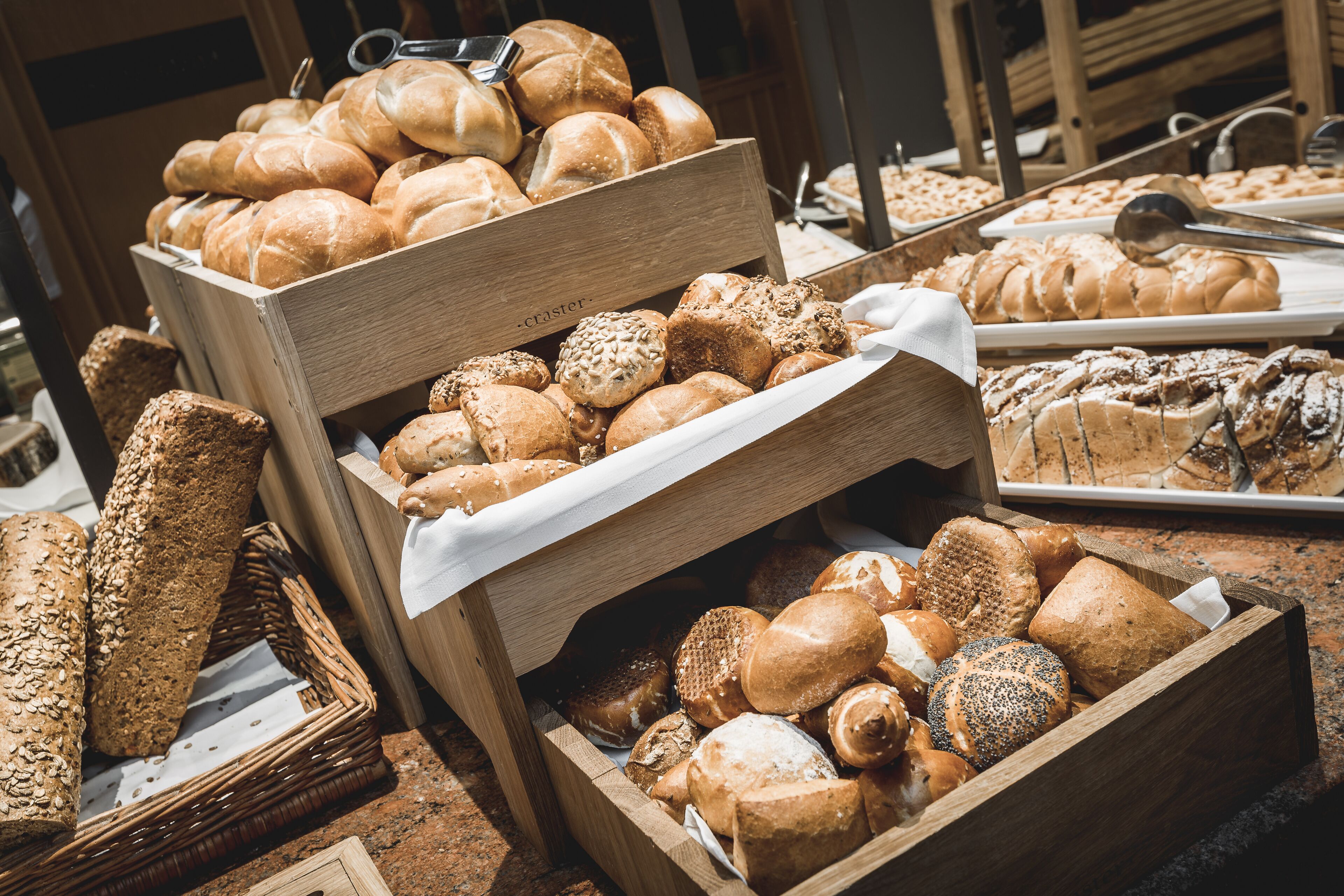 A variety of breads and pastries displayed in wooden boxes.