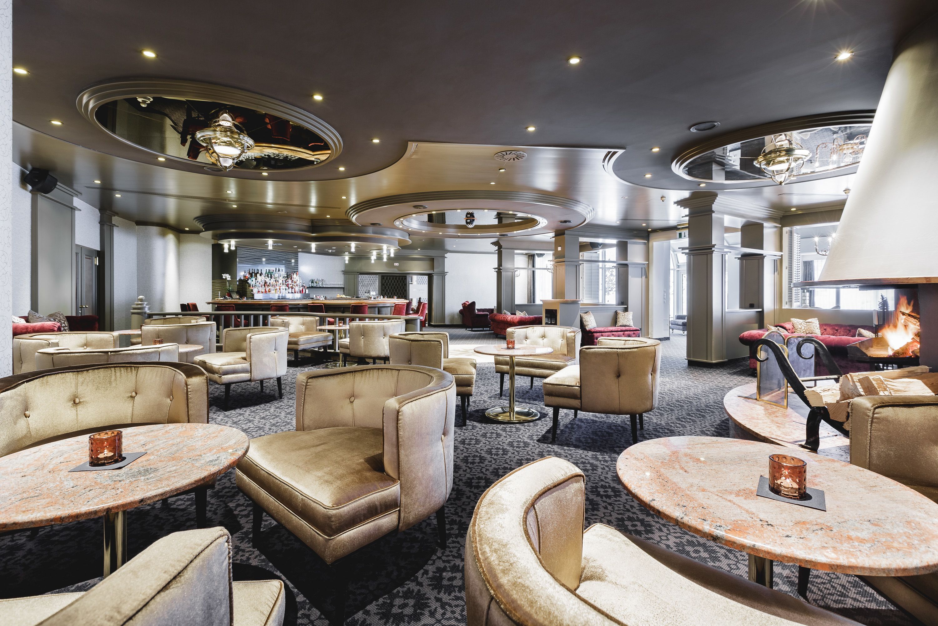 A spacious lobby with multiple seating areas, a bar, and a fireplace.