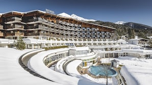 Un hotel de varios pisos con el nombre de una estación de esquí, un área de piscina y paisajes nevados.