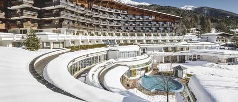 Un hôtel à plusieurs étages, dont le nom évoque une station de ski, avec une piscine et des environs enneigés.