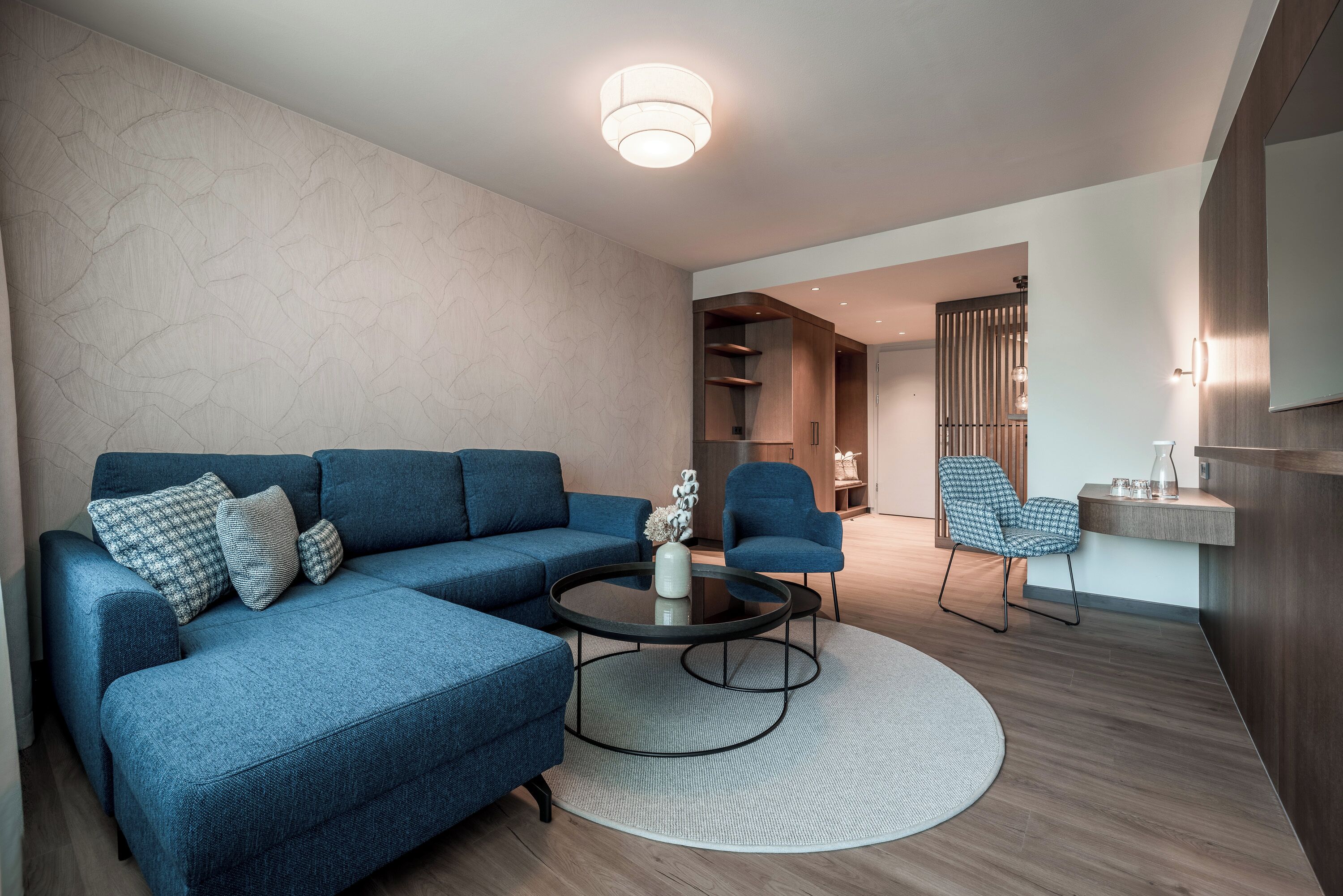 Una sala moderna con un sofá modular, una mesa de centro redonda y un sillón azul.