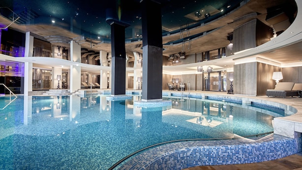 Una amplia piscina interior con agua cristalina, rodeada de arquitectura moderna y varios niveles de balcones.