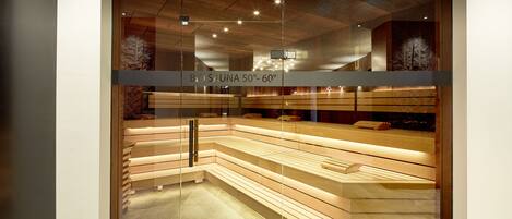 A glass-fronted spa area with wooden benches and a sign indicating a temperature range of 50-60 degrees.