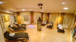 Een kamer met meerdere loungestoelen, een centrale lantaarn en een groot raam met gordijnen.