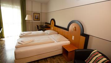 A hotel room with a double bed, a desk, a chair, a lamp, and a picture on the wall.