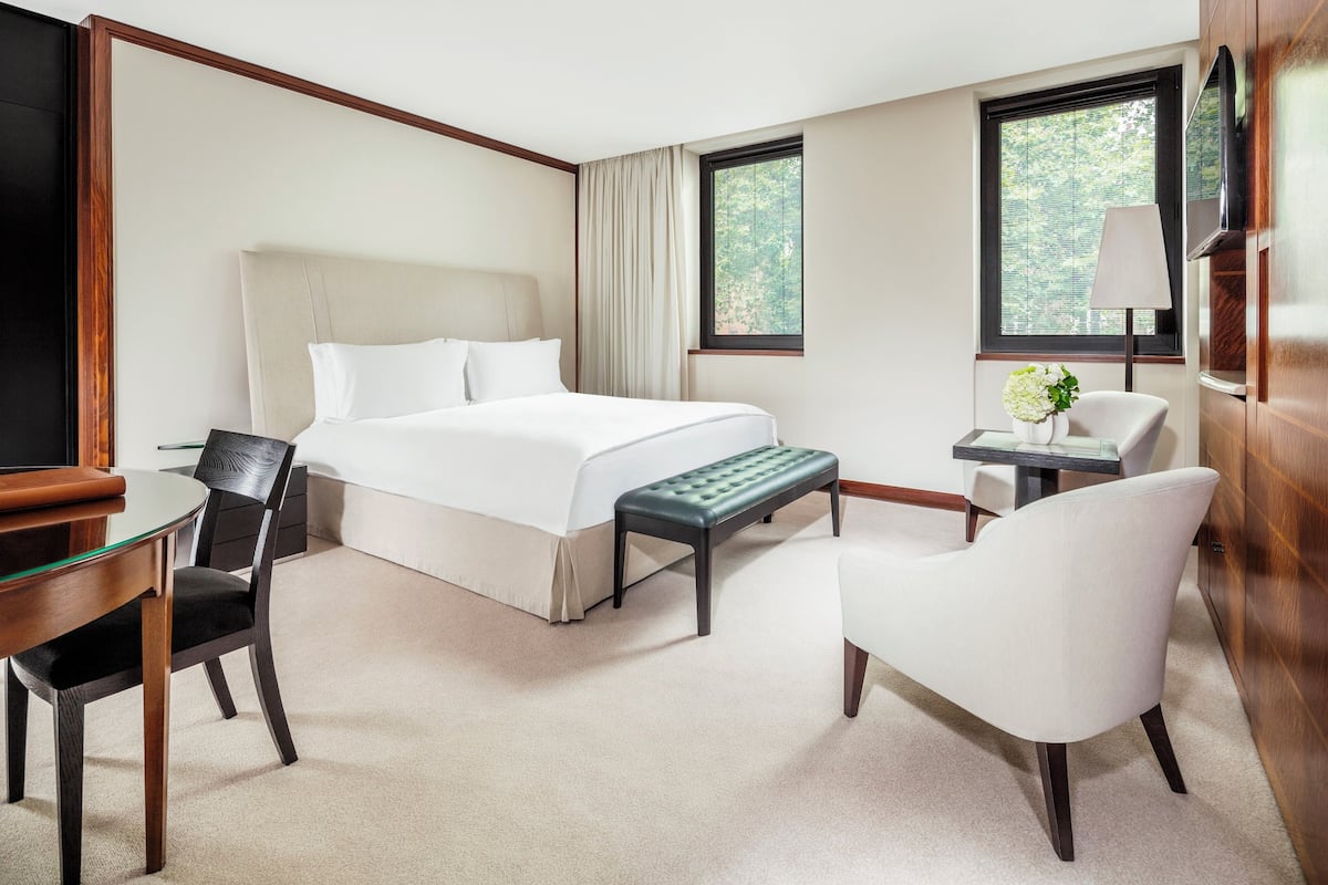 Une chambre d’hôtel comprenant un lit, un bureau, une chaise, un banc et un téléviseur.