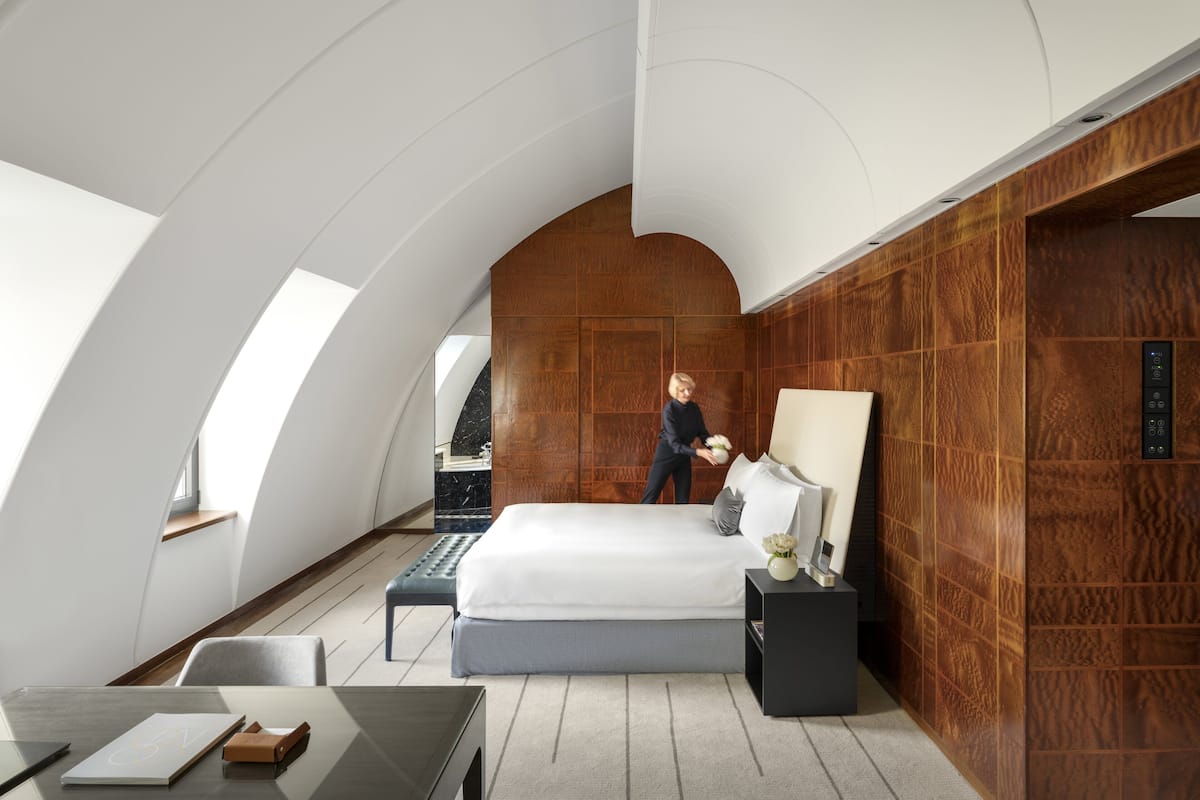Une chambre moderne avec un grand lit, un bureau et un mur d’accent en bois.