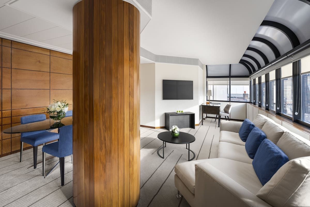 Un intérieur moderne avec un mur d’accent en bois, un canapé avec des coussins bleus, une table basse ronde et un téléviseur à écran plat fixé au mur.