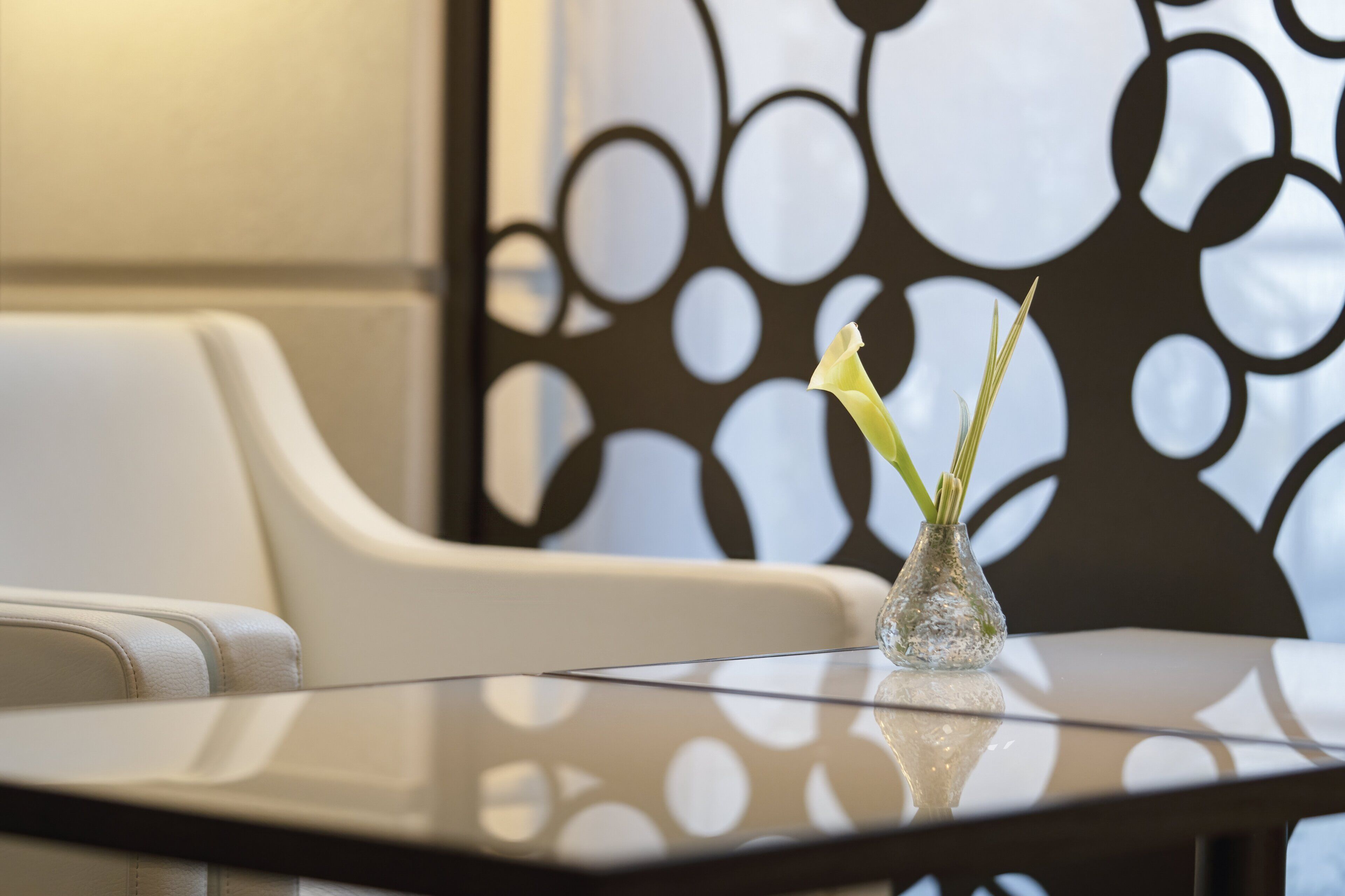 A glass table with a vase containing a single white flower.