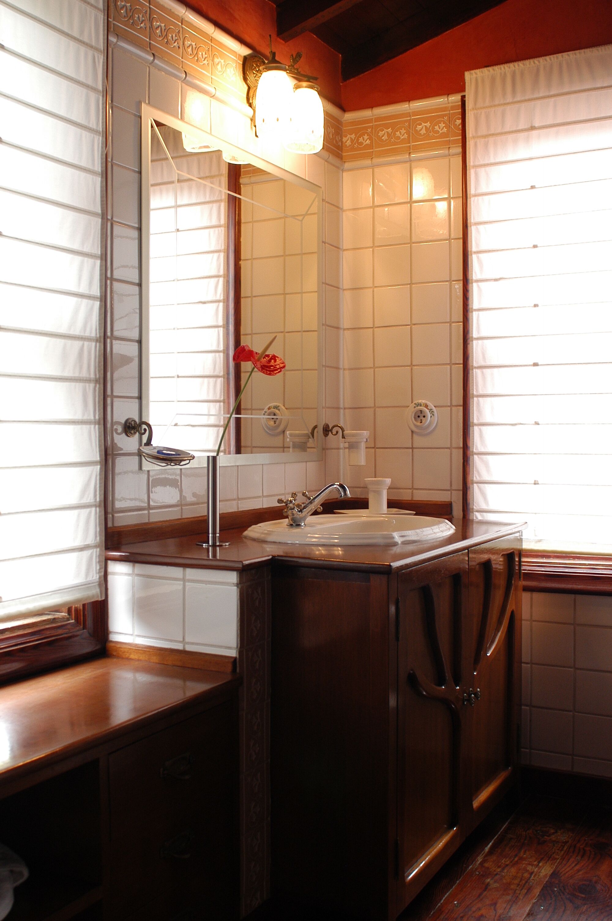 Un baño con tocador de madera, lavabo, espejo y lámpara.
