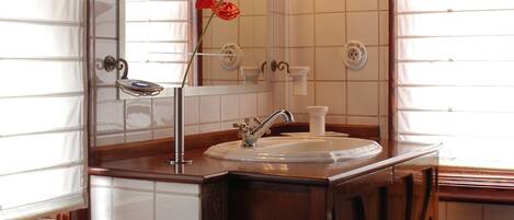 Un baño con tocador de madera, lavabo, espejo y lámpara.