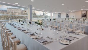 A long dining table set with white tablecloths, silverware, and glassware, with chairs on both sides. - DoubleTree by Hilton Edinburgh City Centre (Edinburgh)