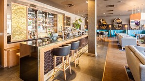 A bar area with stools, a counter, and a variety of bottles and glasses. - DoubleTree by Hilton Edinburgh City Centre (Edinburgh)