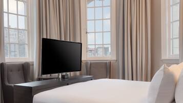 A hotel room with a large bed, a flat-screen TV, a desk, and a chair.
