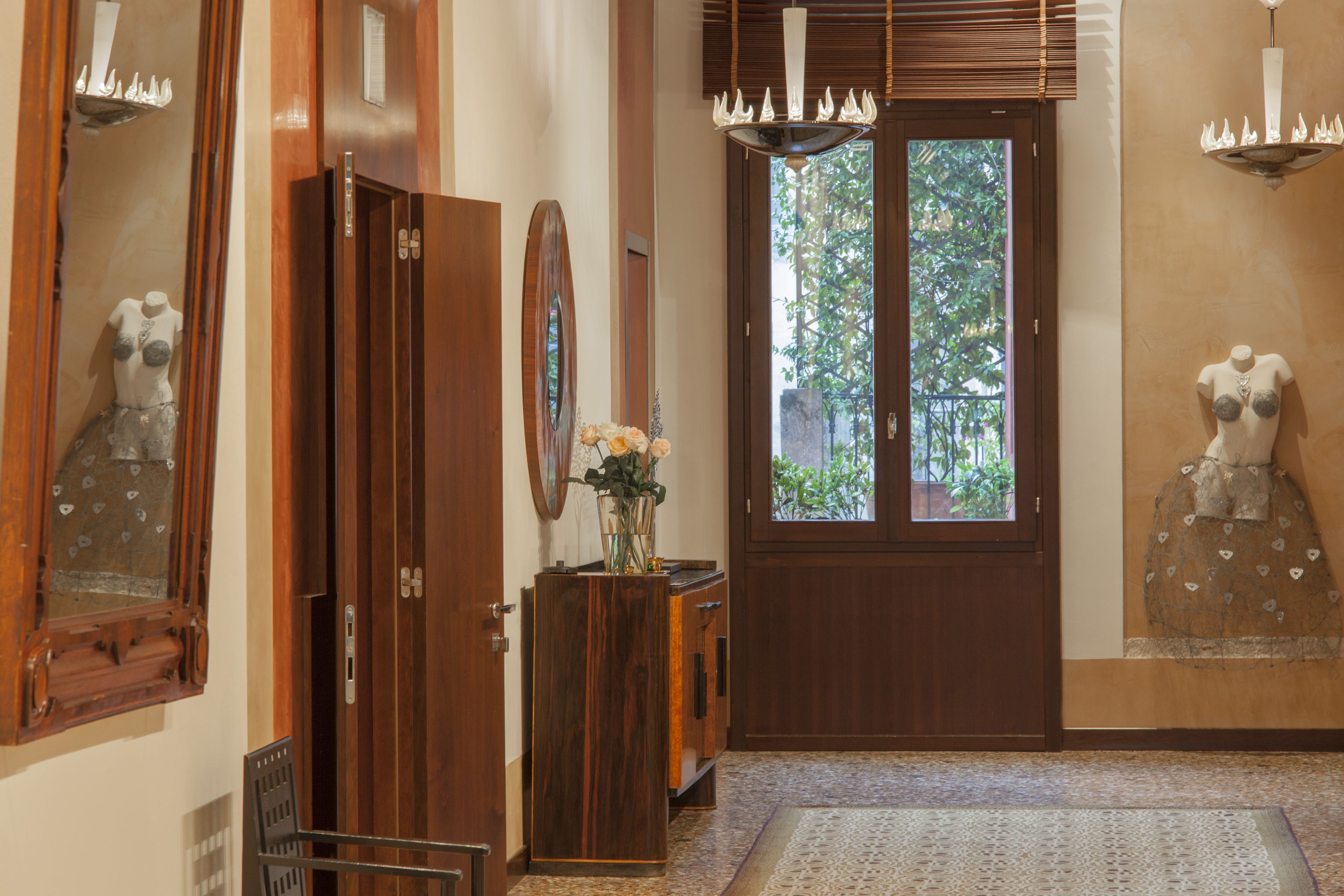 A wooden door with a glass panel, a wooden cabinet with a vase of flowers, and a mannequin on the wall.