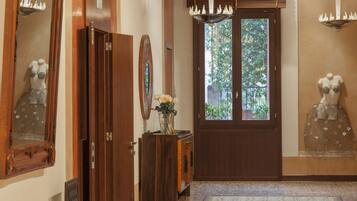 A wooden door with a glass panel, a wooden cabinet with a vase of flowers, and a mannequin on the wall.
