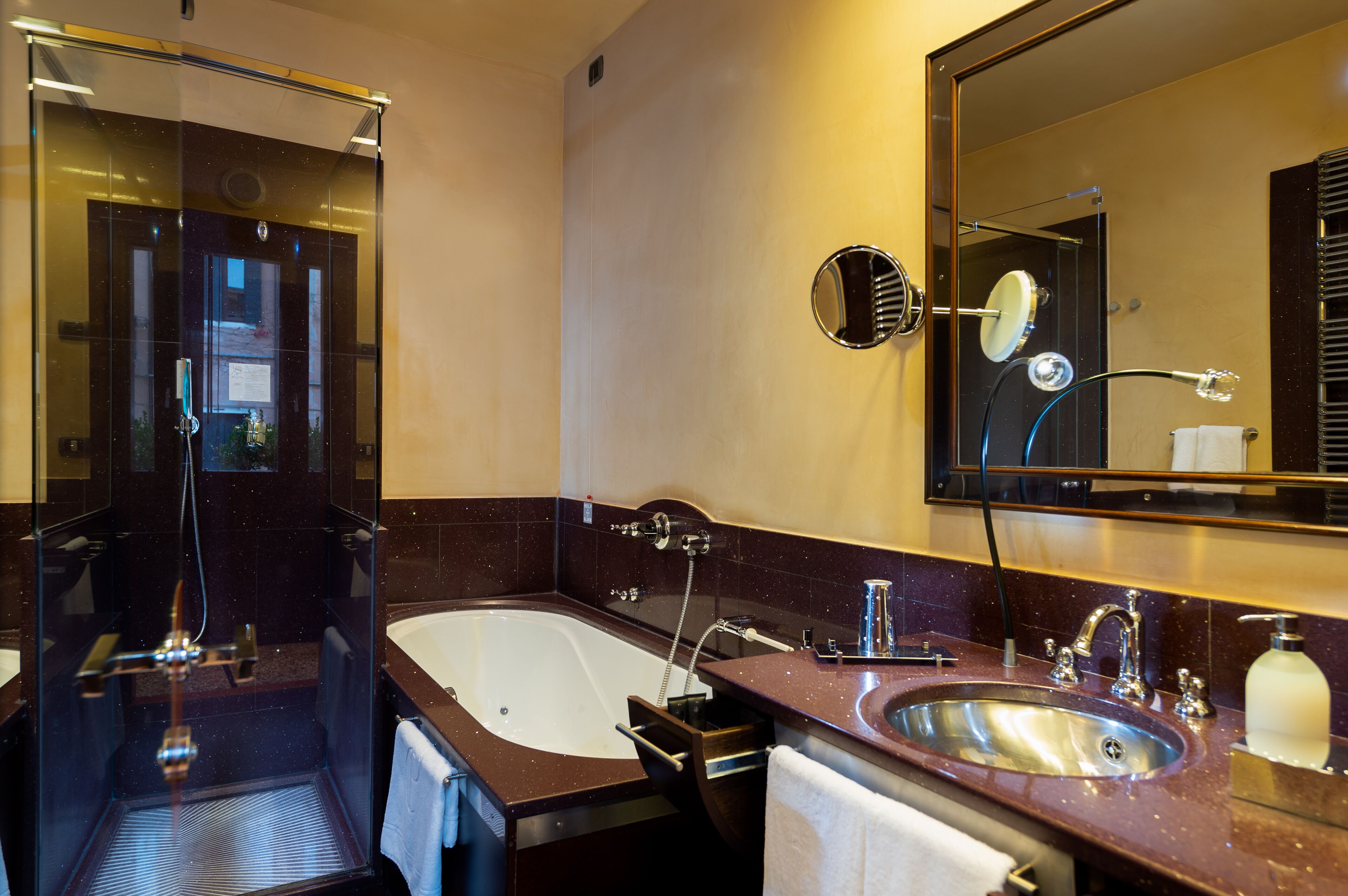 A modern bathroom with a glass-enclosed shower, a large bathtub, a vanity with a sink, and a mirror.