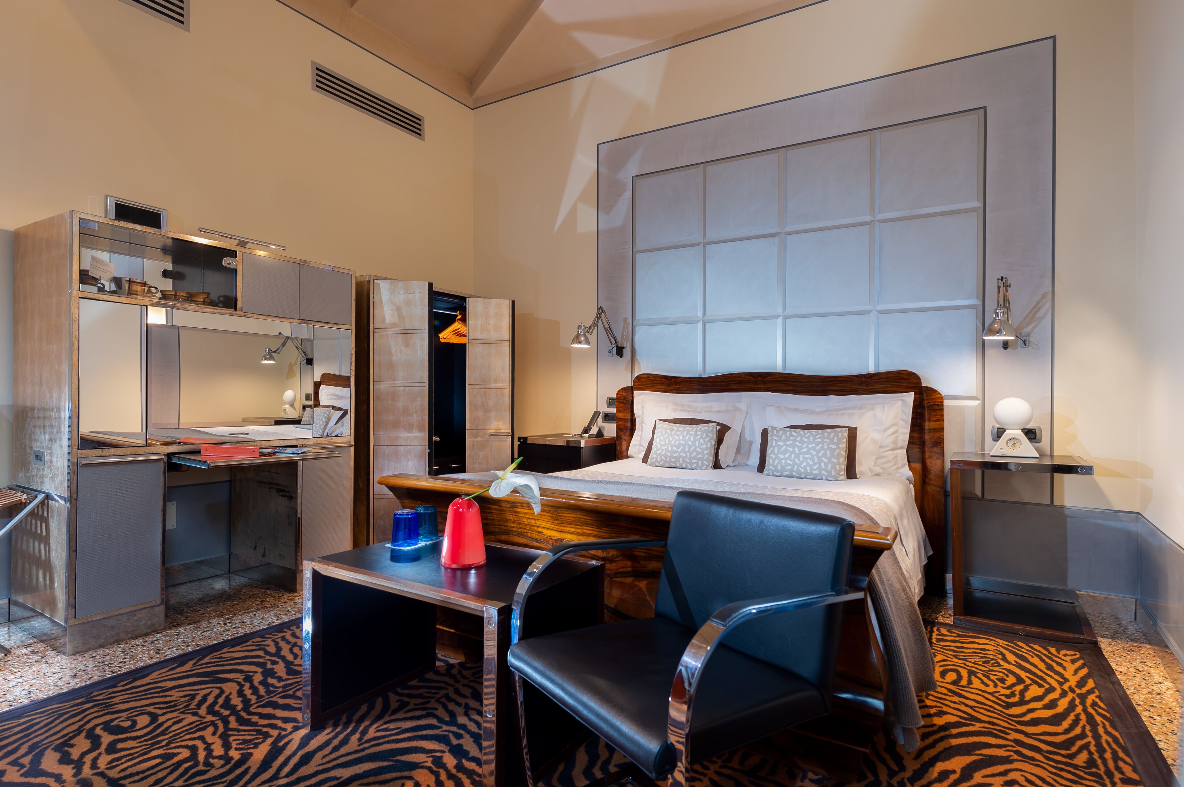 A hotel room with a bed, desk, chair, and a large window.