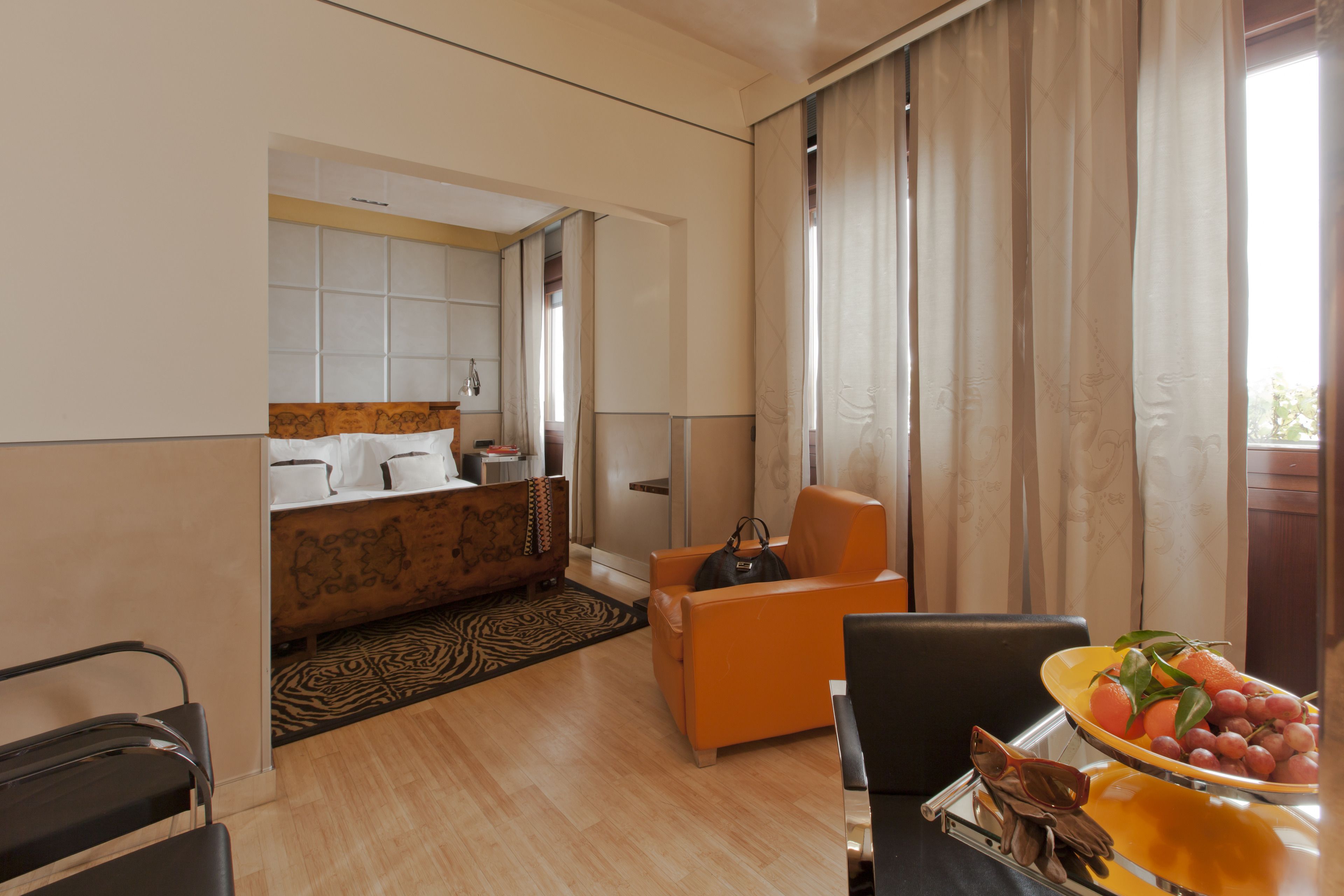 Une chambre d’hôtel avec un lit, un canapé, une table à manger avec des fruits et une vue sur l’extérieur.
