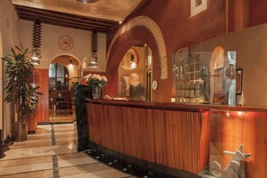 A hotel lobby with a reception desk, wooden paneling, a clock, and a staircase leading to another level. - Ca' Pisani Hotel (Venice)