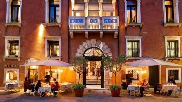 A hotel facade with outdoor seating and a central entrance.
