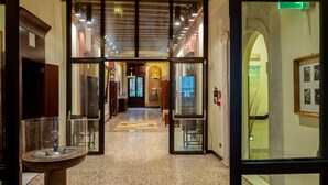 A hotel lobby with a polished stone floor, a reception desk, and a glass partition.