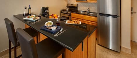 A modern kitchen with wooden cabinets, a stainless steel refrigerator, and a central island with seating.