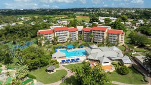 Un hotel con varios pisos, piscina y cancha de tenis.