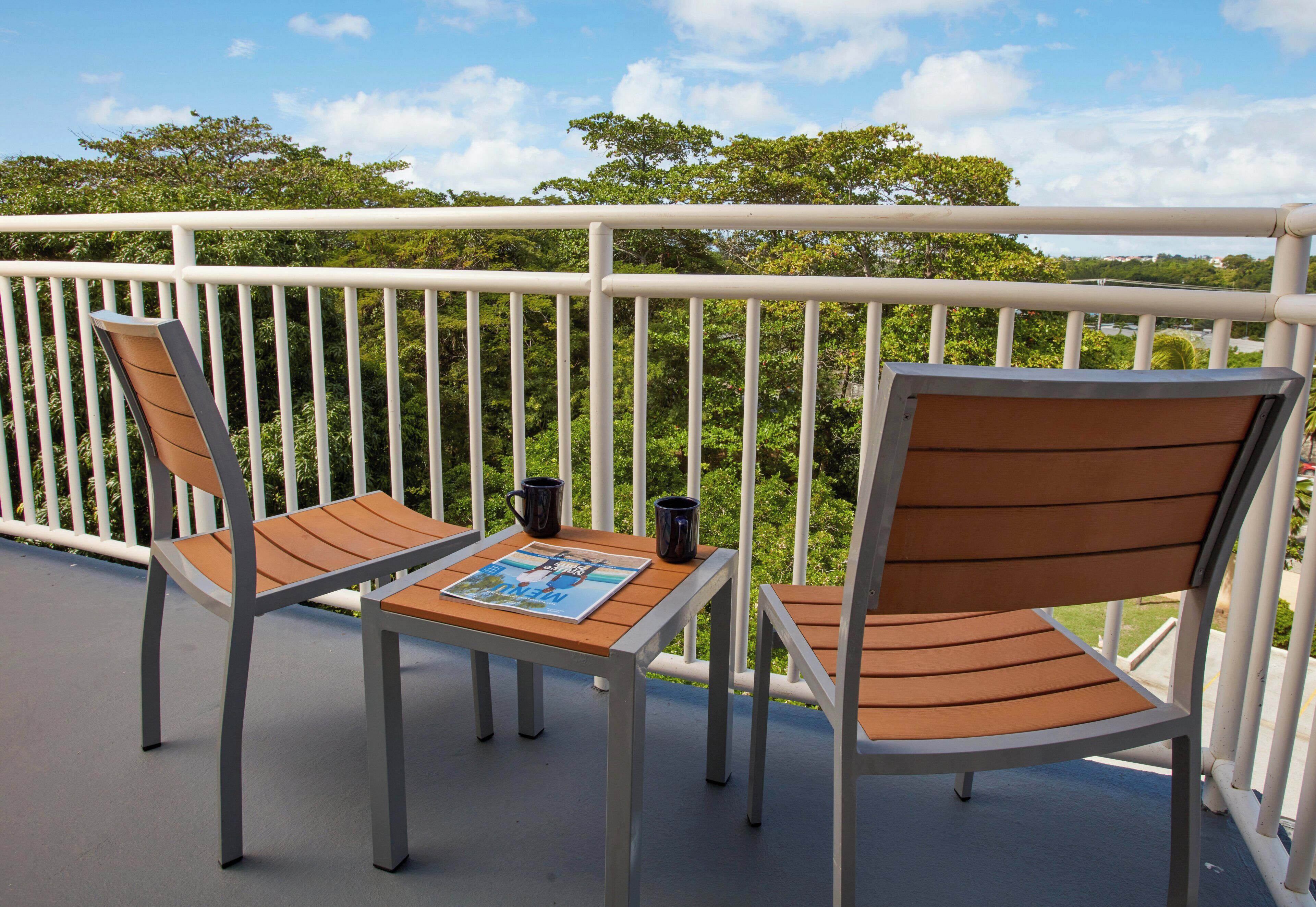 Un balcon avec deux chaises et une table, un magazine et deux tasses.