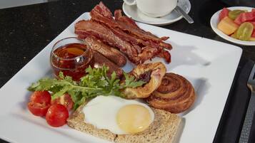 Un plato de desayuno con tocino, huevos, tostadas y tomates.
