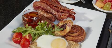 Une assiette de petit-déjeuner composée de bacon, d’œufs, de pain grillé et de tomates.