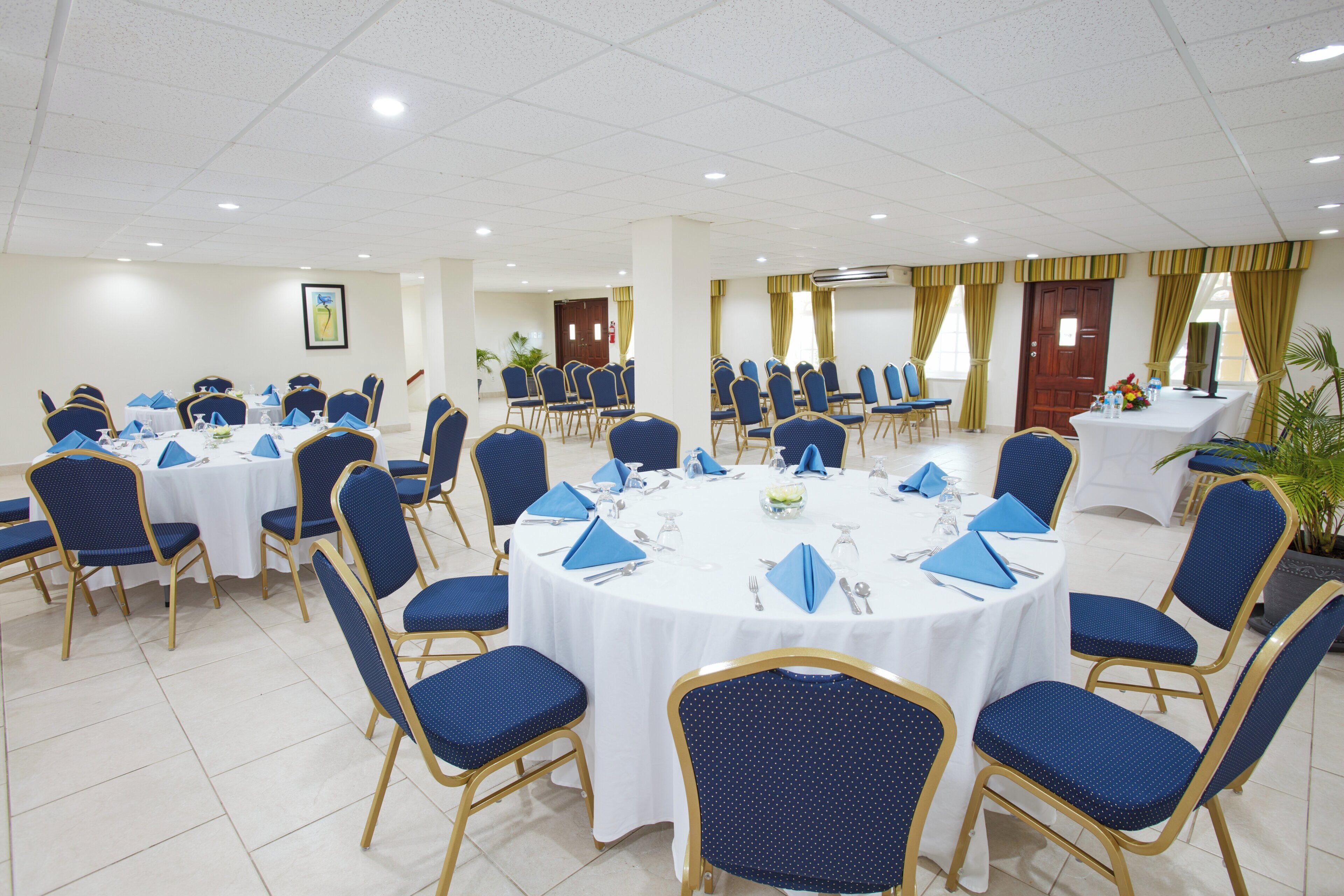Un salón de conferencias con mesas redondas, sillas azules y manteles blancos.
