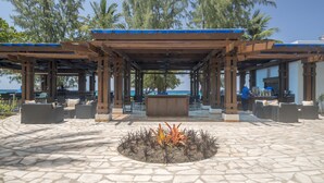 Un espacio al aire libre con piso de piedra, pérgola de madera y una chimenea.