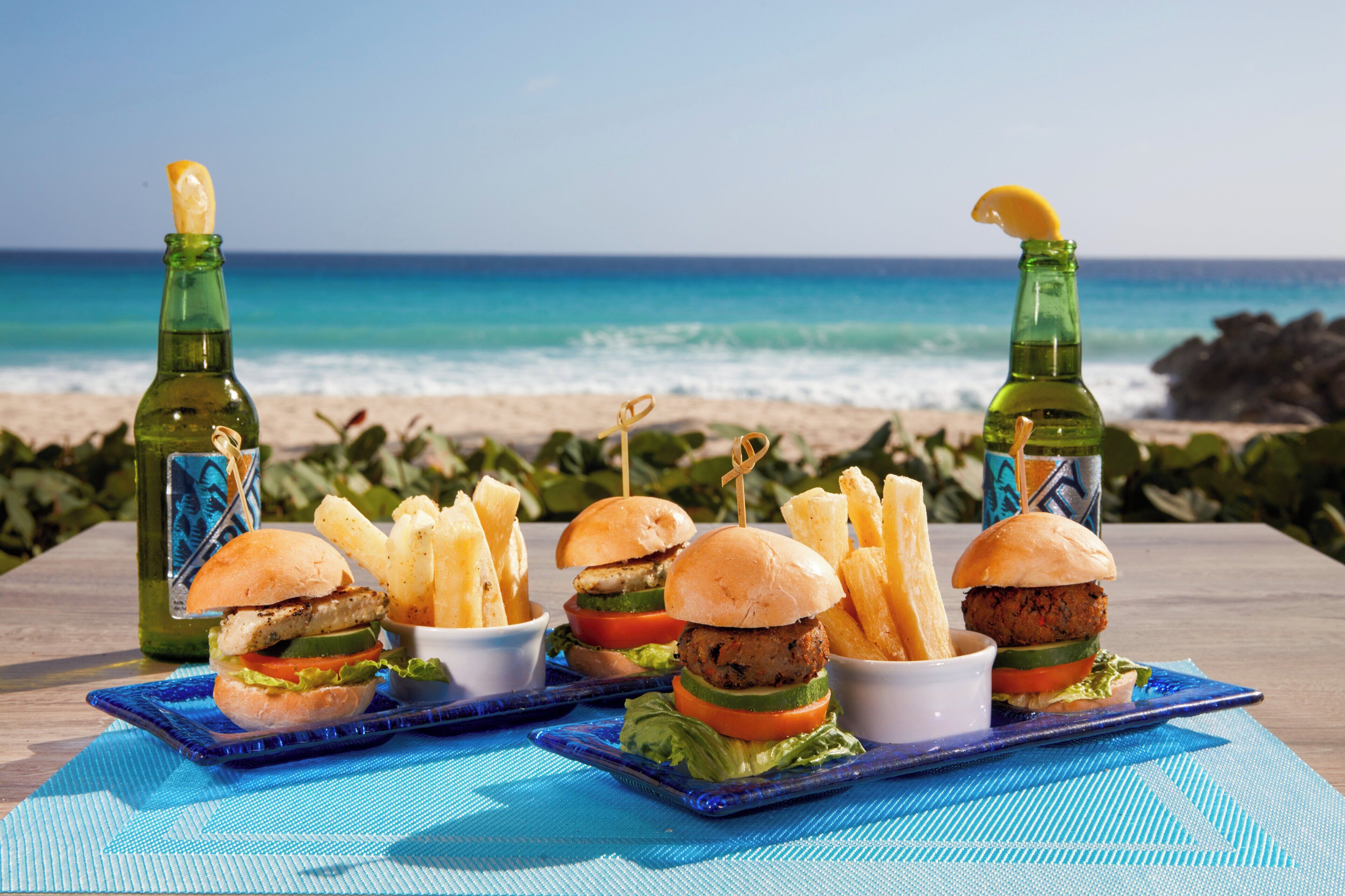 A table with food and drinks on a beach with ocean in the background.