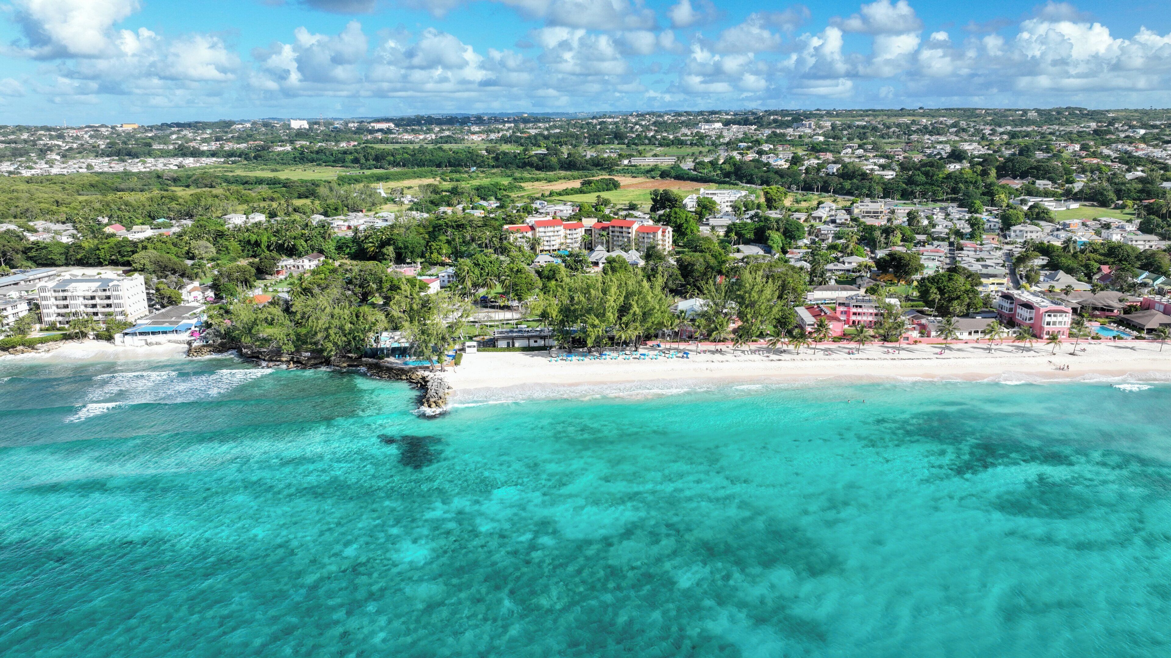 A coastal town with a beach, clear turquoise waters, and a mix of residential and commercial buildings.