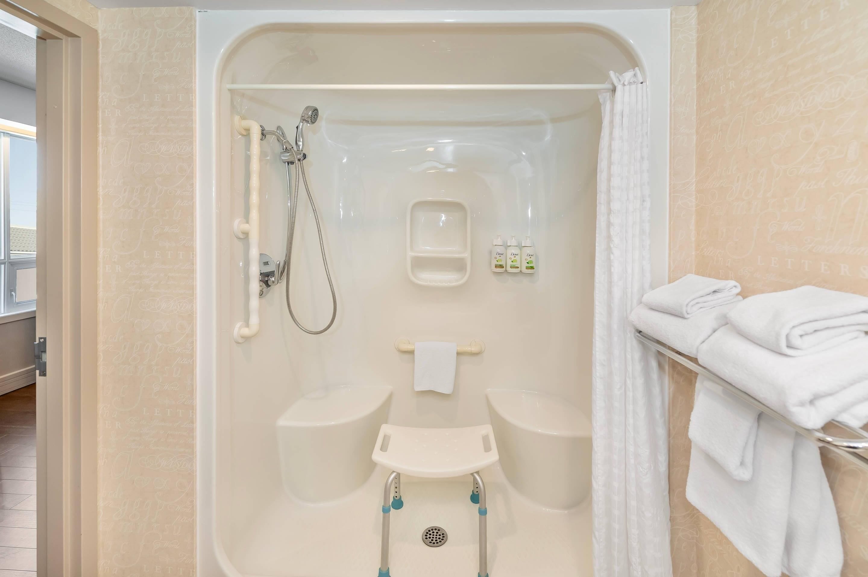 A bathroom with a shower, two sinks, a grab bar, and a towel rack.