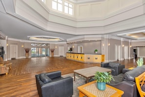 A spacious lobby with a reception desk, seating area, and a view of the outside.