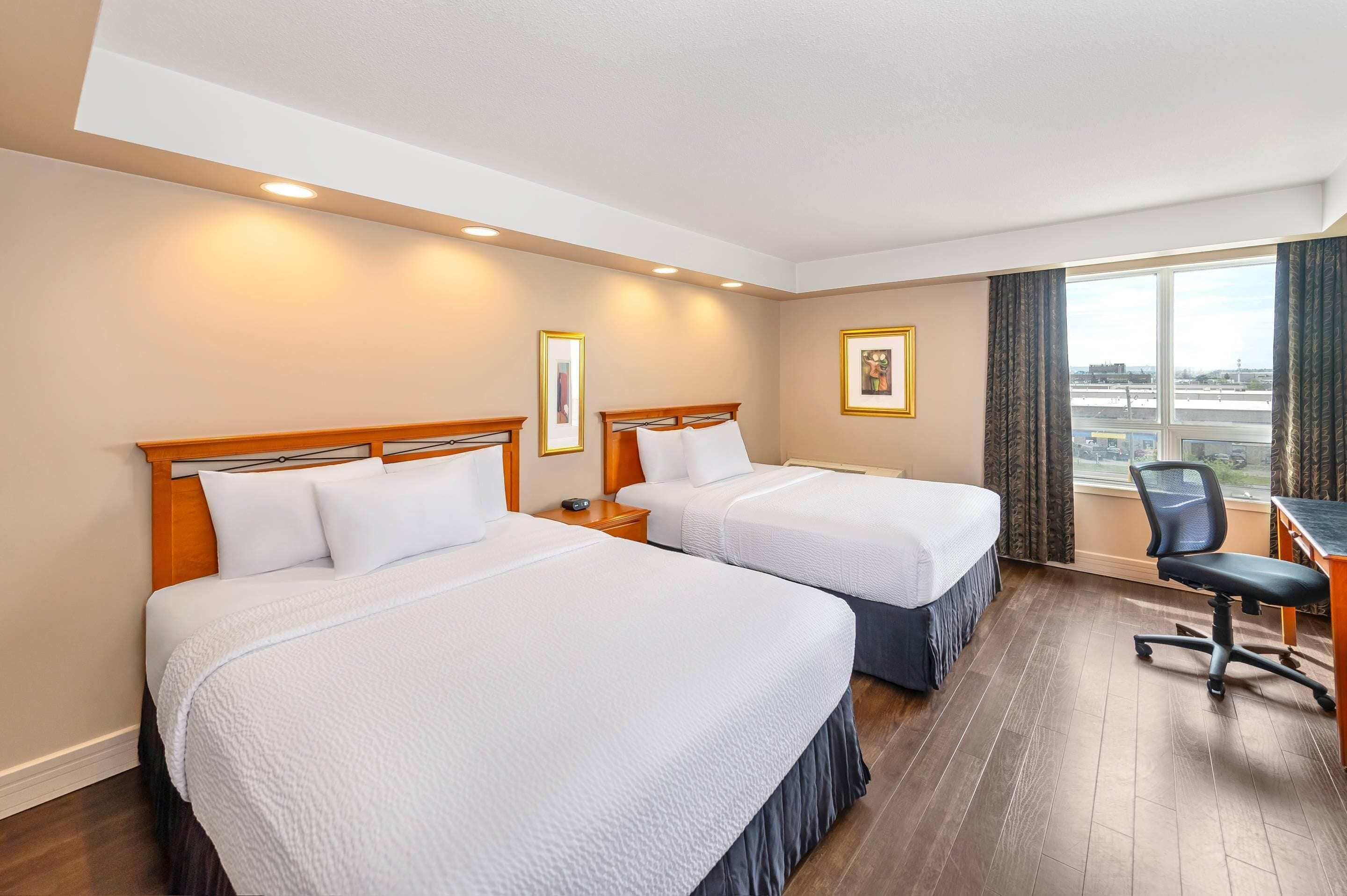 Ein Hotelzimmer mit zwei Betten, einem Schreibtisch und einem Stuhl.