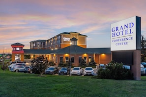 A hotel with a prominent sign, multiple parking spaces, and a well-maintained lawn.
